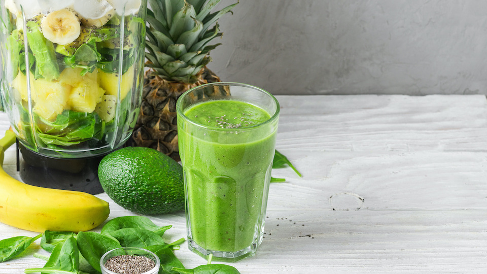 Glass of green smoothie detox with fresh juicy ingredients in blender for making healthy drink. Cooking concept